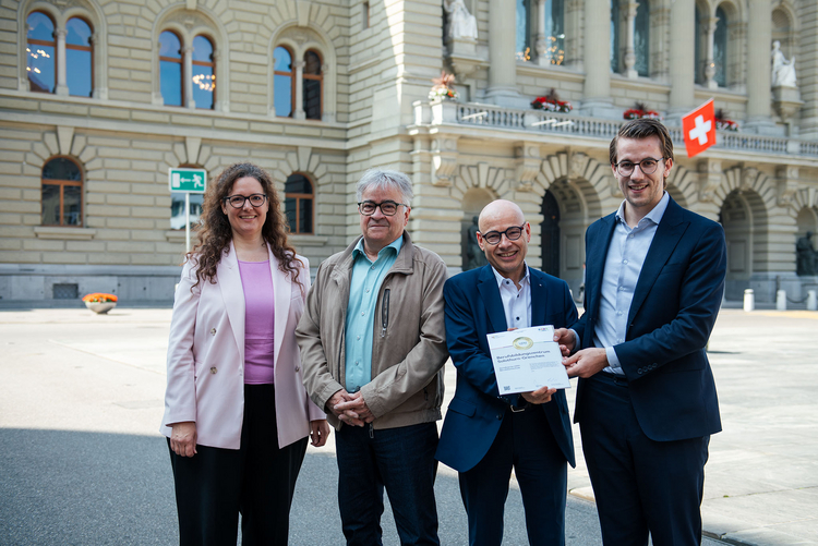 Direktor Bernhard Beutler steht mit mehreren Personen vor dem Bundeshaus und hält das unternehmerisches Engagement Gold-Zertifikat in seinen Händen