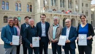 Direktor Bernhard Beutler steht mit mehreren Personen vor dem Bundeshaus und hält das unternehmerisches Engagement Gold-Zertifikat in seinen Händen.