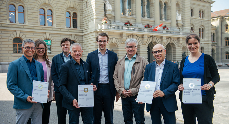 Direktor Bernhard Beutler steht mit mehreren Personen vor dem Bundeshaus und hält das unternehmerisches Engagement Gold-Zertifikat in seinen Händen.